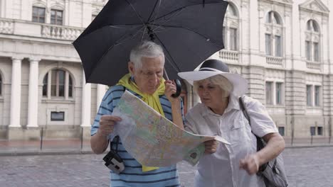 turistas varones y mujeres mayores caminando con un mapa en las manos buscando una ruta