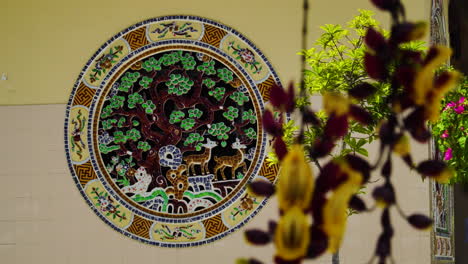 Mosaic-in-Buddhist-temple,-Mysore-trumpetvine-flowers-in-foreground