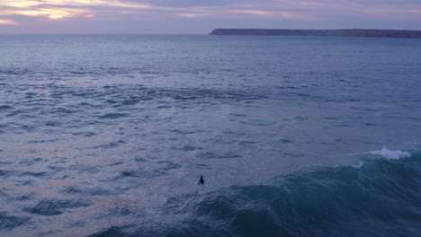 Lonely-surfer-at-Praia-do-Tonel-Portugal-during-sunset,-aerial