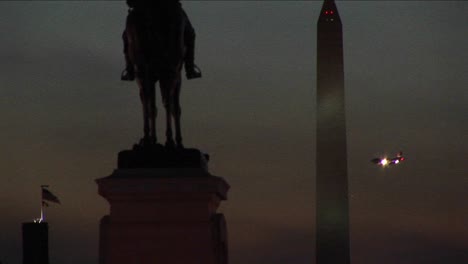 a statue of ulysses s grant is in silhouette in the foreground of the washington monument on a cloudy night