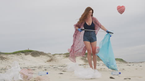 animación de corazones sobre mujer caucásica recogiendo basura en la playa