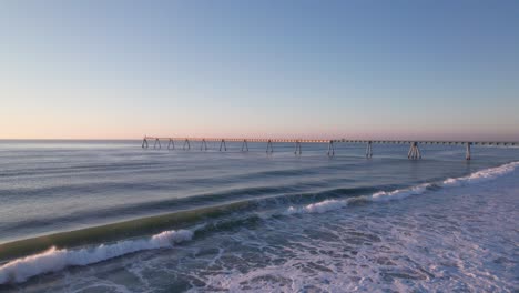 coastal sea bridge and ocean waves hitting coastline, aerial drone view