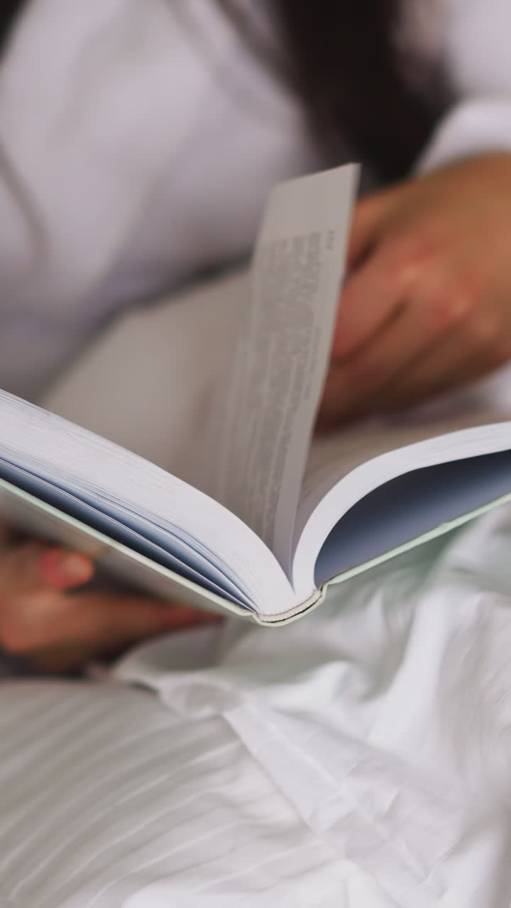 Woman turns book pages with husband in bed closeup. Lady in bathrobe reads story resting with boyfriend in home bedroom. Routine for tight sleeping