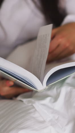 woman turns book pages with husband in bed closeup. lady in bathrobe reads story resting with boyfriend in home bedroom. routine for tight sleeping