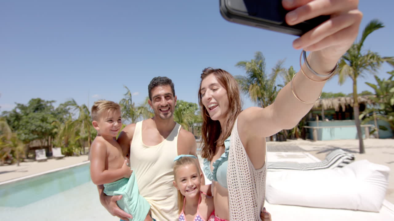 Happy caucasian family taking selfie with smartphone at beach house