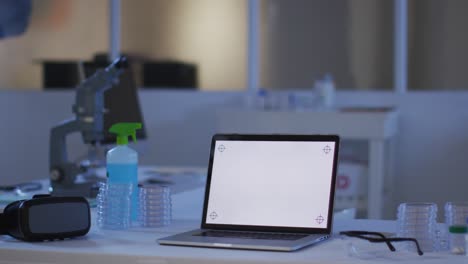 Laptop-with-illuminated-screen-at-a-workstation-in-an-empty-laboratory