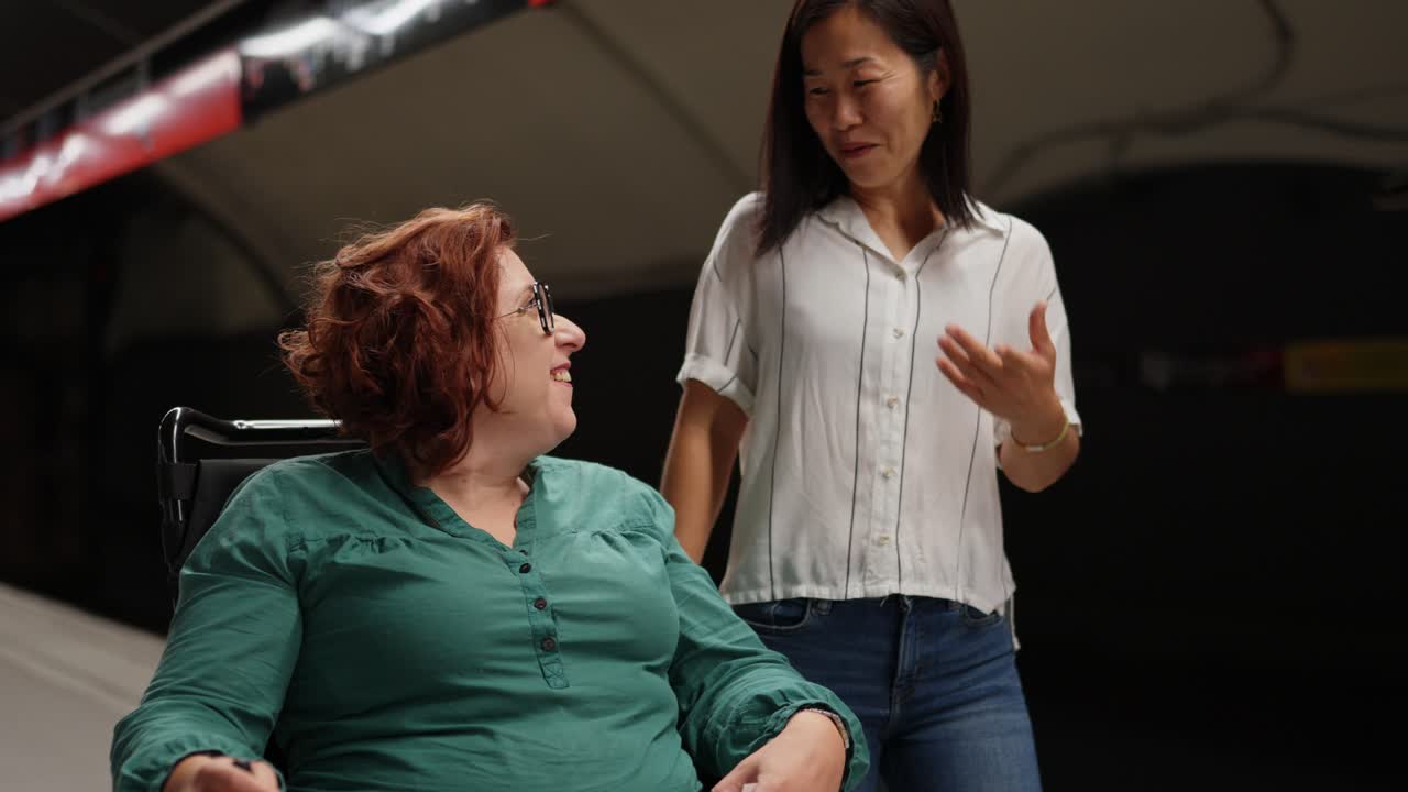 Two friends at a subway station, one in a wheelchair