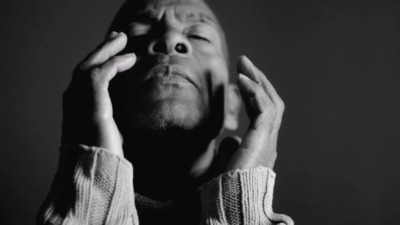 orando a dios con las manos juntas en fondo gris negro con la gente stock video stock footage