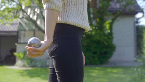 close-up view of a woman hand holding a petanque ball and getting ready to throw it in the park