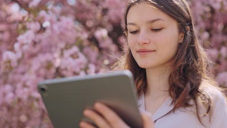 young woman using tablet in a spring park