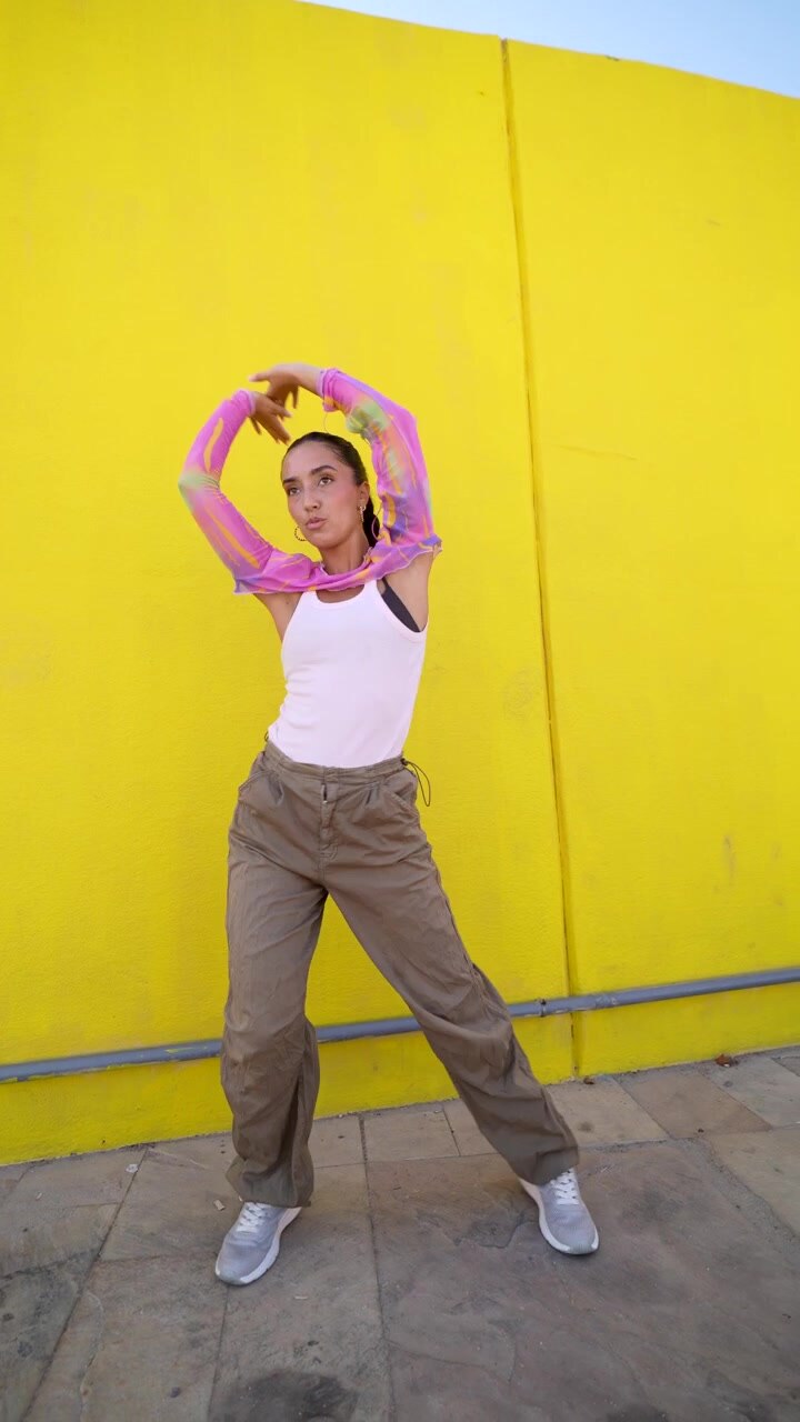 Young Woman Dancing in Front of a Bright Yellow Wall
