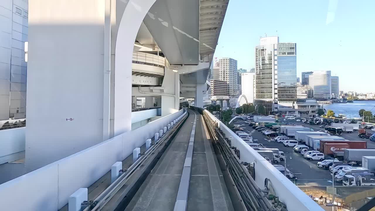 A monorail glides through Tokyo's cityscape, capturing urban architecture and vibrant skies in bright daylight
