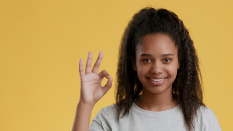 rapariga adolescente sorridente com um gesto de mão ok