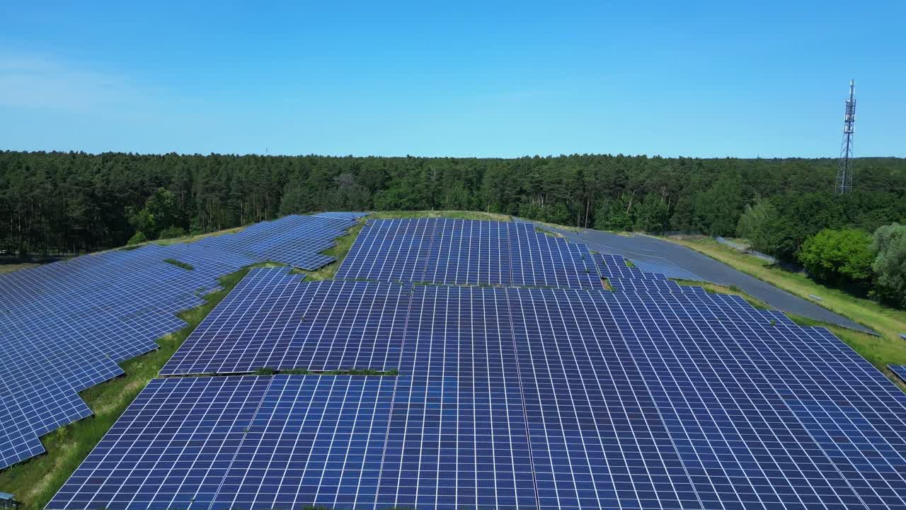 Photovoltaic panels providing clean energy in a solar farm on hill near a forest in Germany. Smooth aerial view flight overflight flyover drone