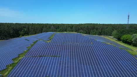 photovoltaic panels providing clean energy in a solar farm on hill near a forest in germany. smooth aerial view flight overflight flyover drone