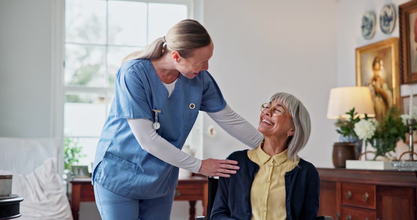 Friendly Nurse Comforting Senior Woman in Wheelchair at Home