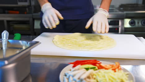 pita on a table. man`s hands put white souce on a top. place with ingredients stand at side. tasty junk food.
