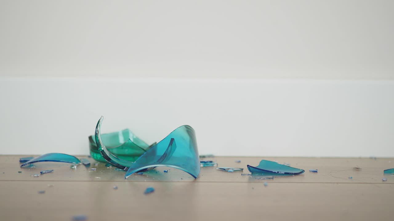 나무 바닥에 부서진 파란 유리의 클로즈업