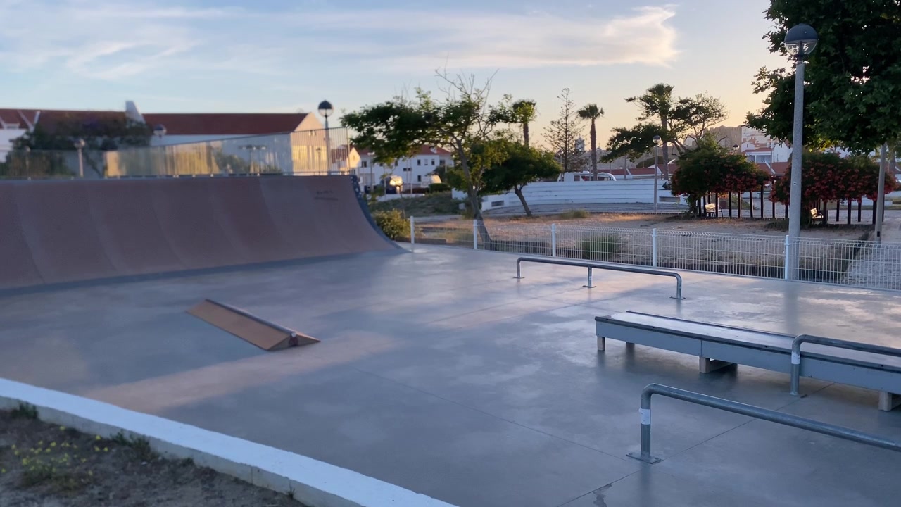 Skateparkelementen zoals een halfpipe, rails en ramps, badend in het zachte licht van het gouden uur, klaar voor actie.