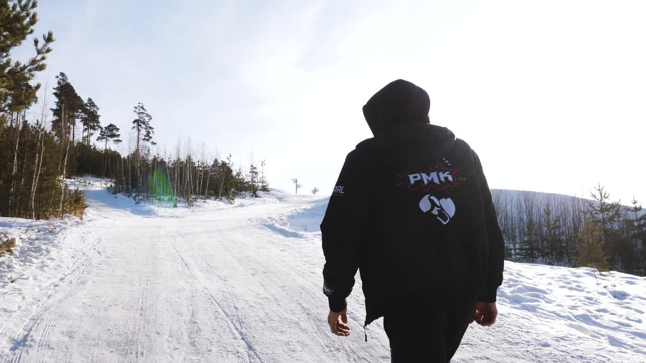 Uomo in piedi su una strada innevata in una foresta