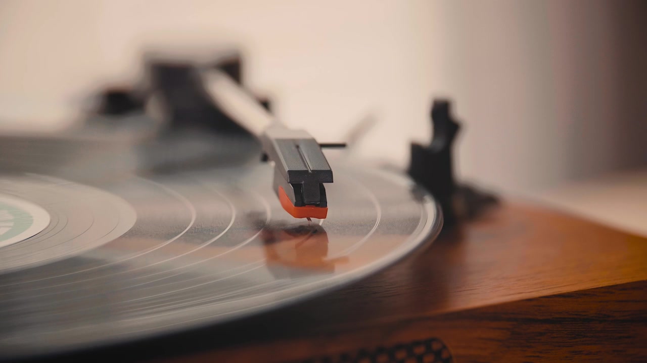 Primo piano di una mano che avvia la riproduzione di un disco in vinile su un giradischi