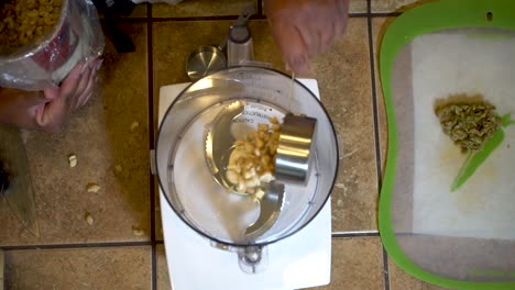 pouring cashew nuts into a food processor, view from above