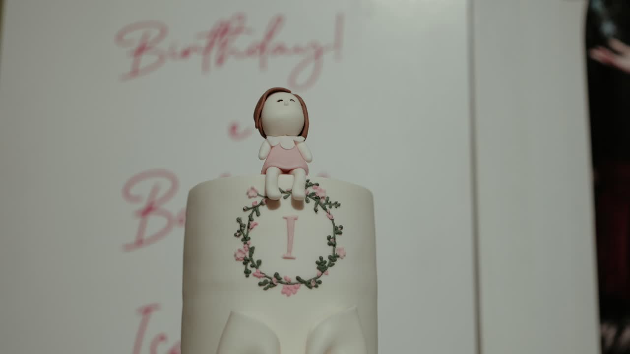 Primo piano di torta del primo compleanno con statuetta di bambola e ghirlanda con il numero uno