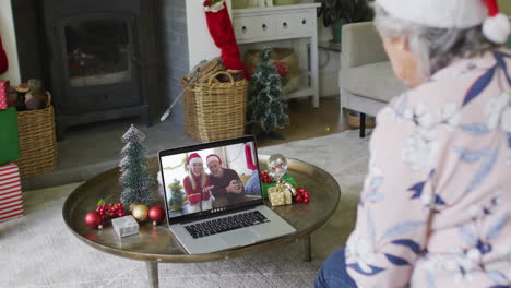 Mujer-Caucásica-Mayor-Saludando-Y-Usando-Una-Computadora-Portátil-Para-Una-Videollamada-Navideña-Con-Una-Pareja-En-La-Pantalla