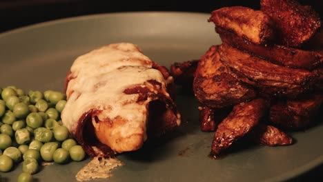 filete de pollo a base de plantas envuelto en tocino vegano con pimentón, patatas rústicas y guisantes
