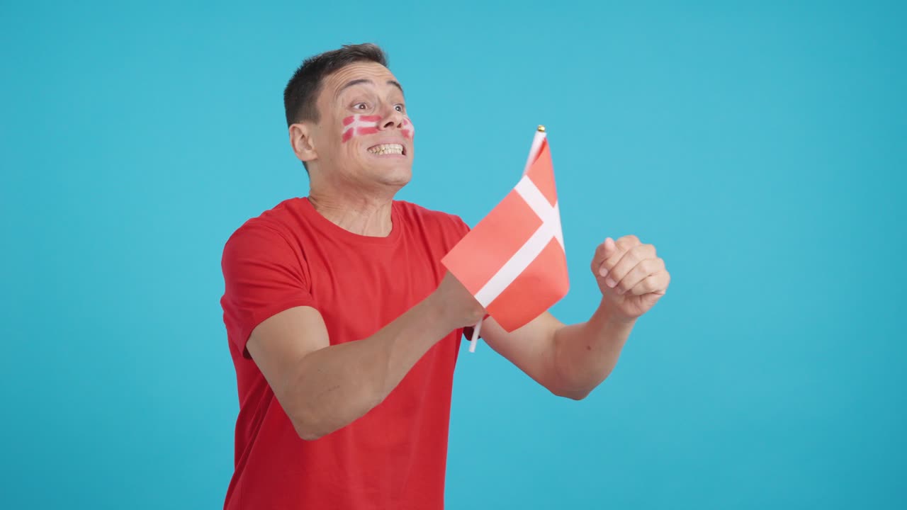 Nervous man cheering for Denmark during a match looking away