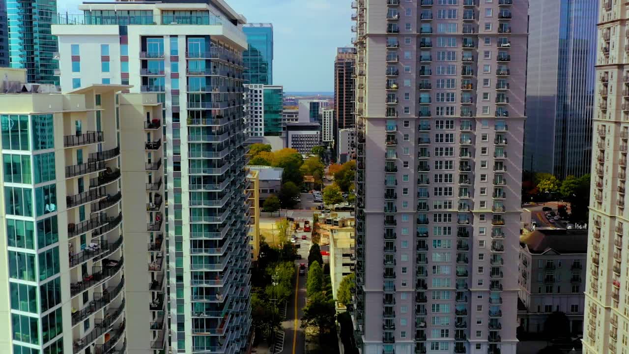 조지아 주 애틀랜타 시내의 초고층 빌딩들 사이에서 피드몬트 파크의 소프트볼 필드 위에서 뒤로 날아다니는 드론 촬영