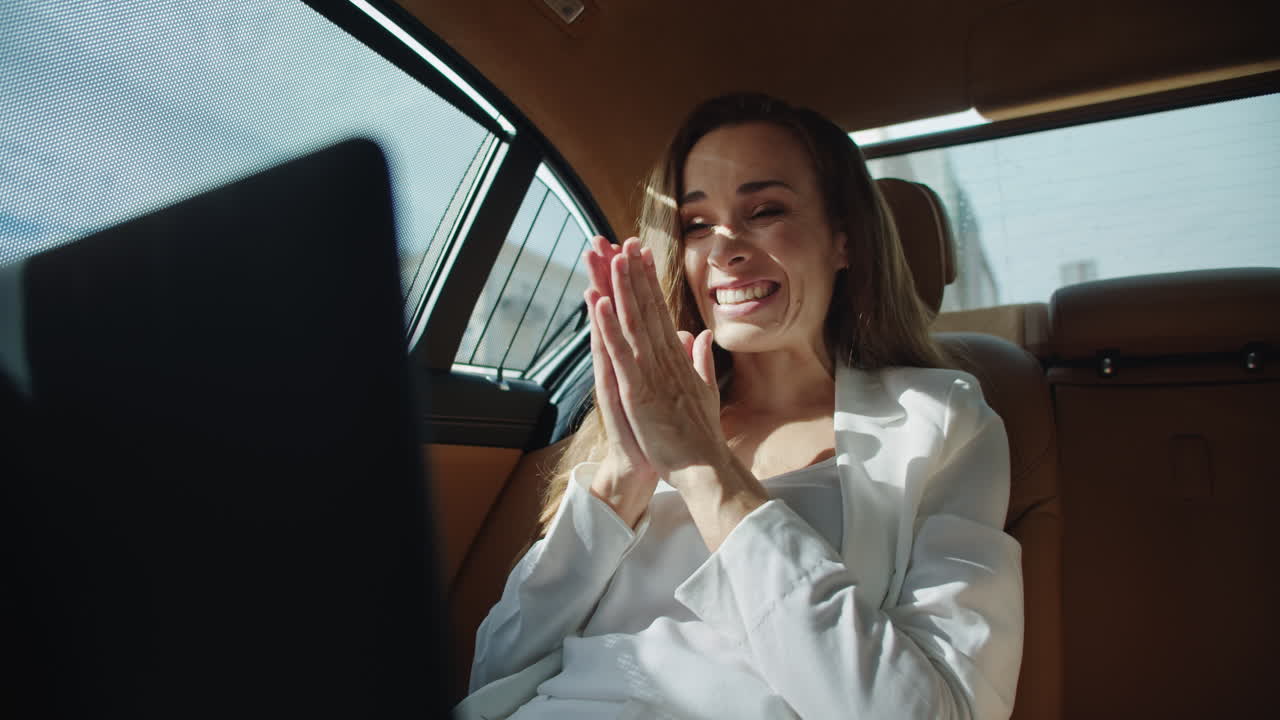 улыбающаяся деловая женщина радуется хорошим новостям на ноутбуке в роскошном автомобиле.