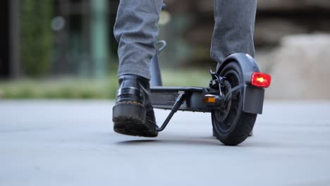 close up of a businessman getting on an e-scooter and driving away