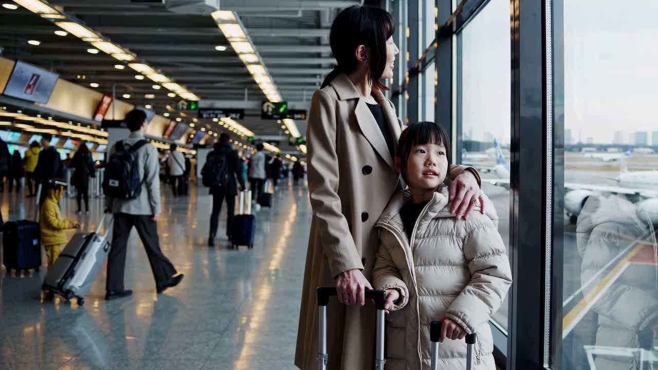 A candid video still of a woman and child at an airport, shot from a side angle, capturing a moment