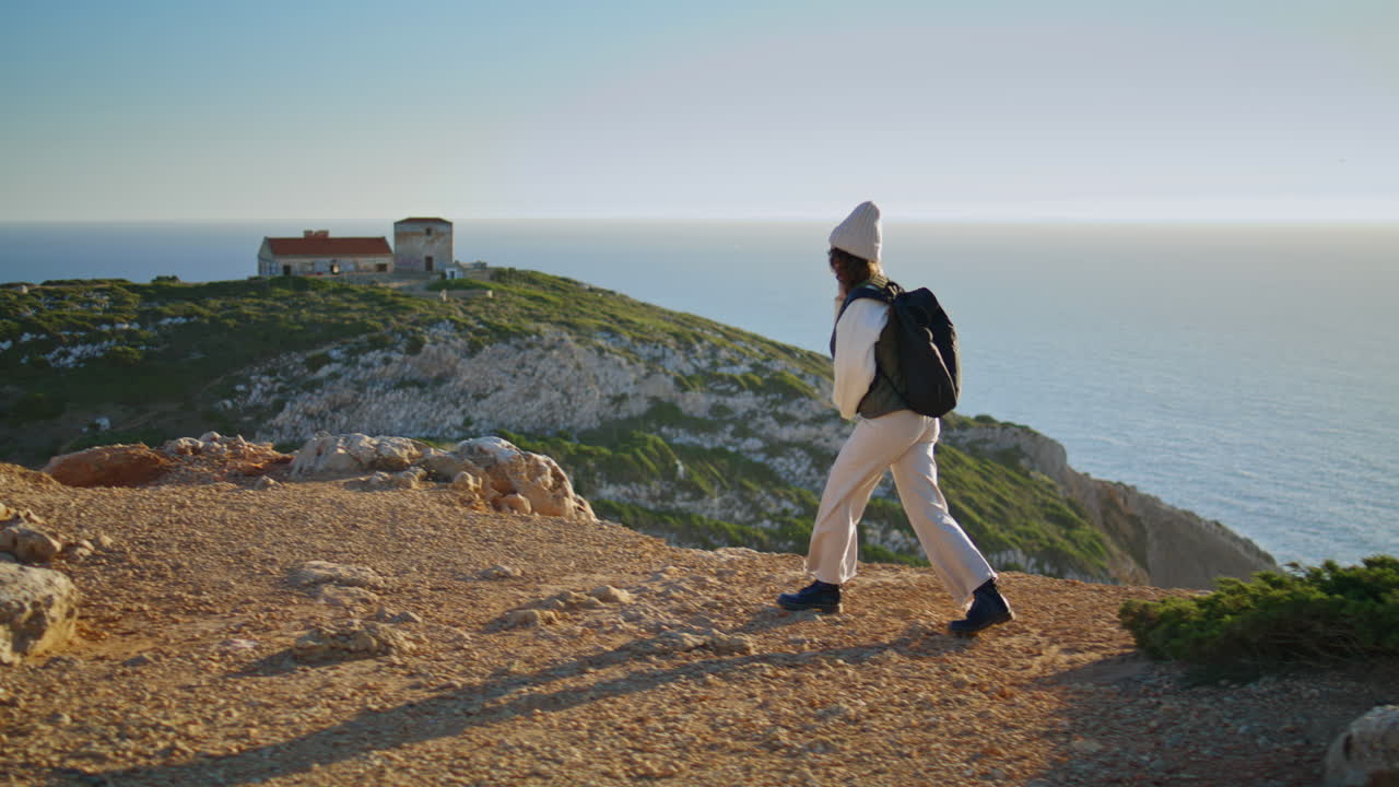 Escursionista che parla al telefono al tramonto sull'oceano calmo. Turista che cammina in montagna.