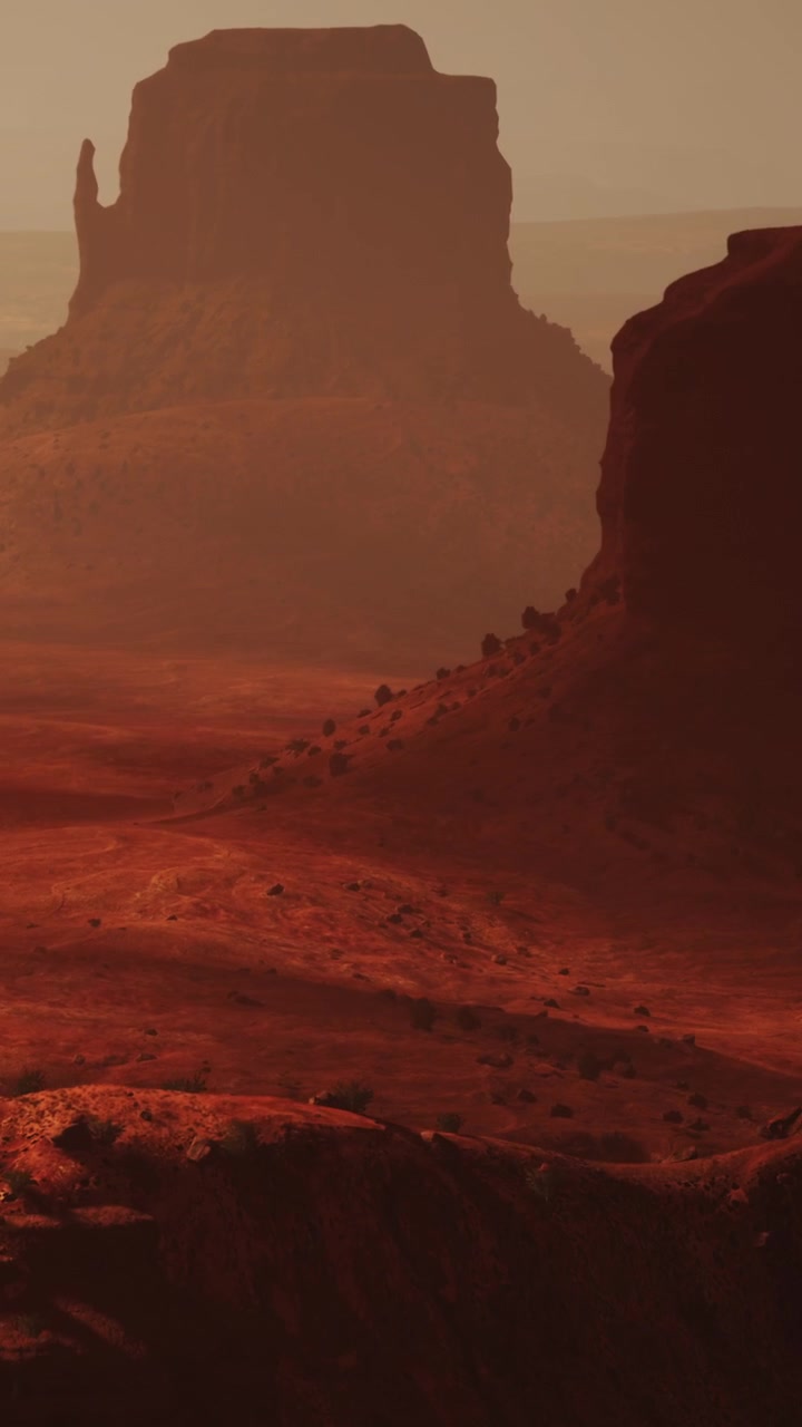 Paesaggio con toni caldi di terra rossa e colline distanti al tramonto