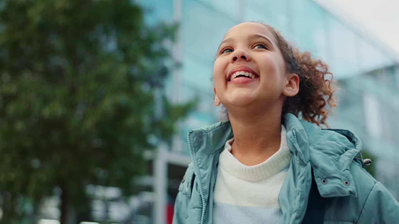 Young girl with curly hair looking up outdoors