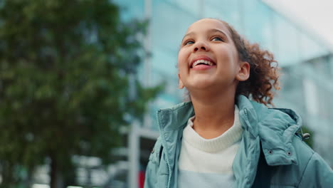 young girl with curly hair looking up outdoors