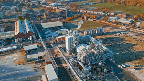 Aerial-footage-moving-towards-a-large-industrial-chemical-plant,-showing-pipelines,-metal-structures,-cooling-towers-and-chemical-storage