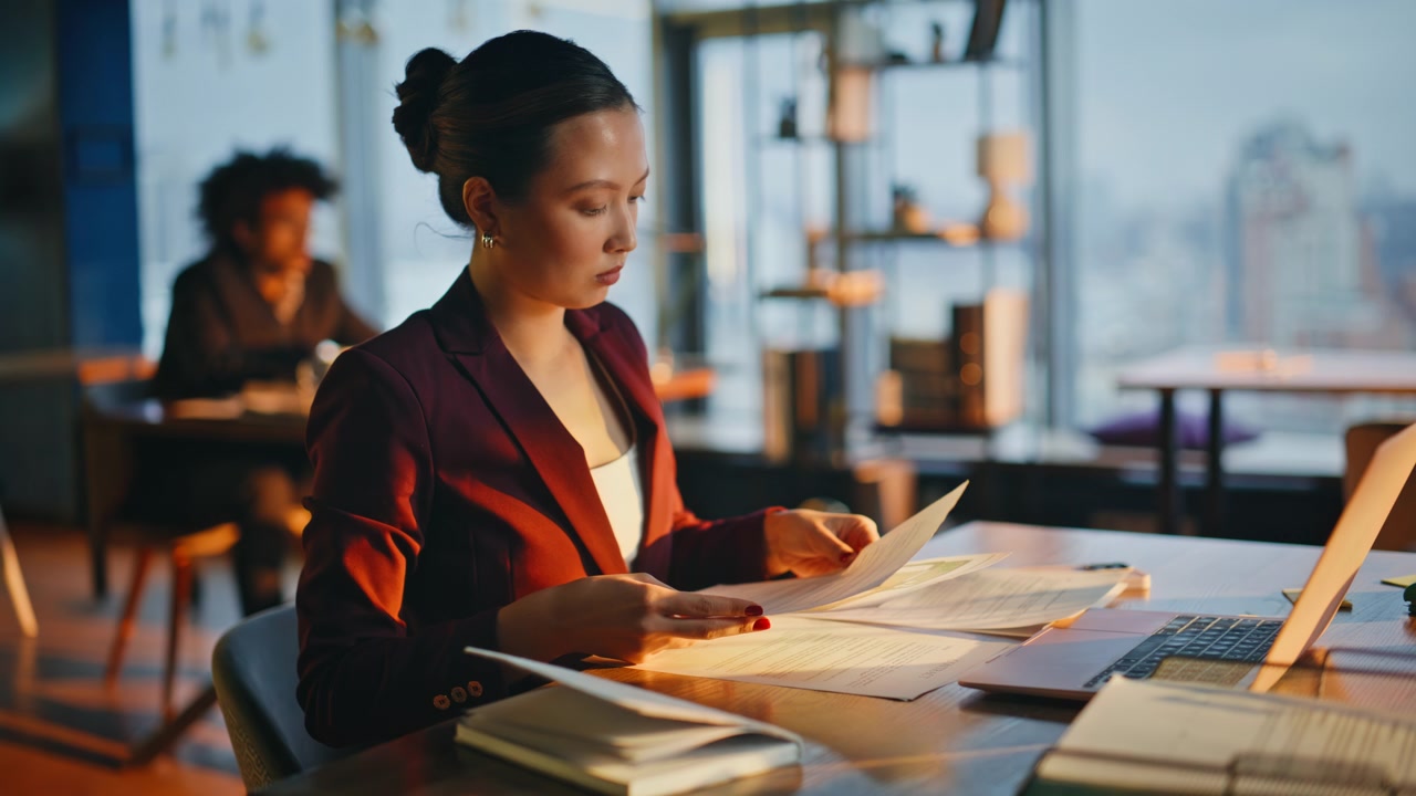 Office worker reviewing papers evening. Asian executive reading contract desk.