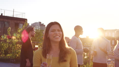 young hispanic woman at a rooftop party smiling to camera