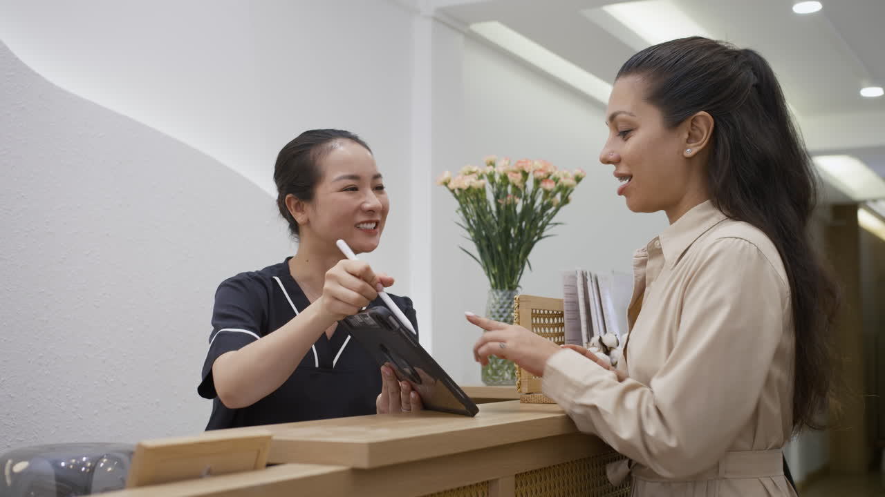 Cheerful Administrator Showing Female Client List of Available Procedures