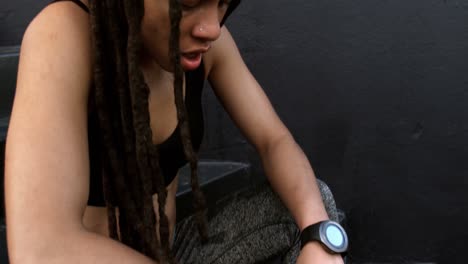 vista lateral de una joven mujer afroamericana relajándose en los escalones de la ciudad 4k