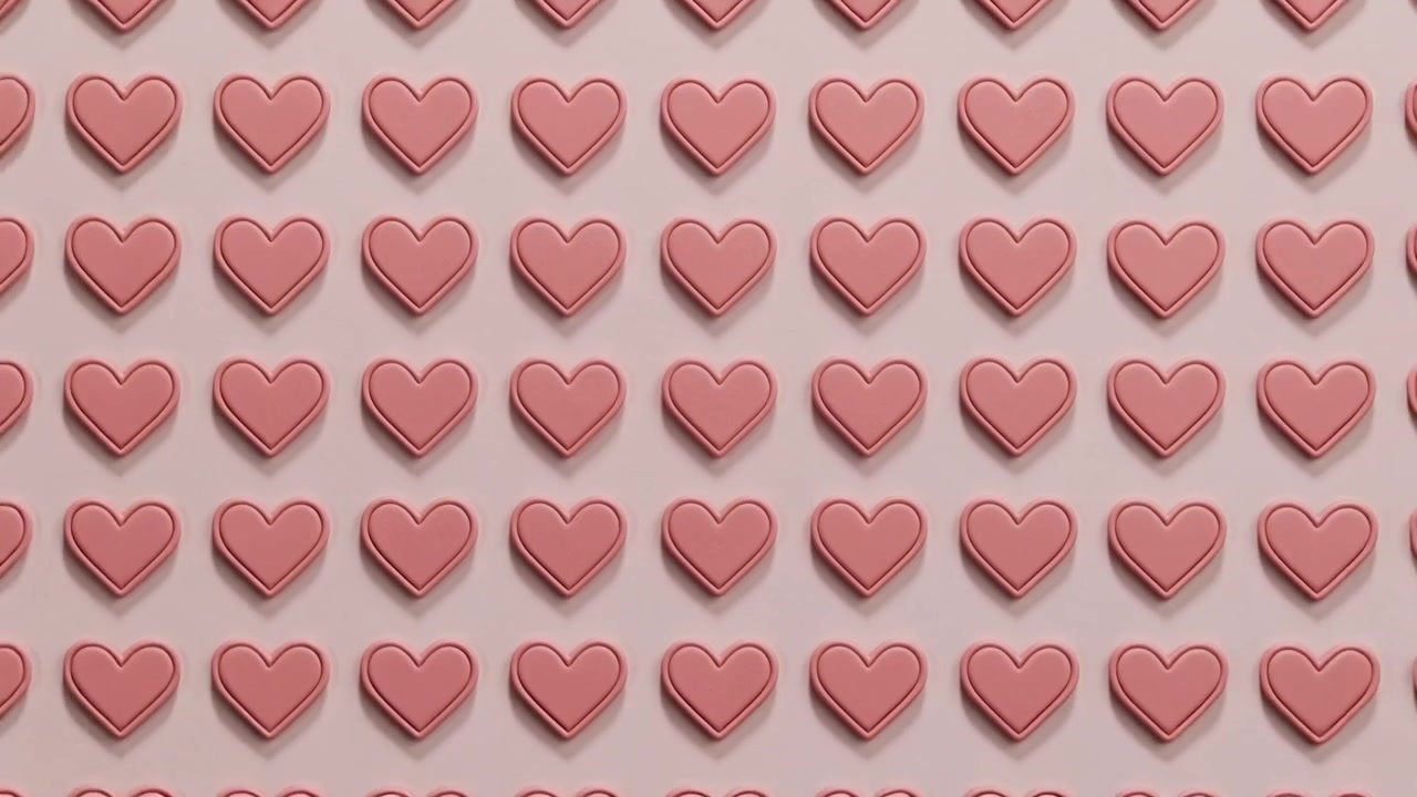La telecamera si allontana, rivelando una griglia di cuori rosa su un tavolo da studio, mostrando un motivo.