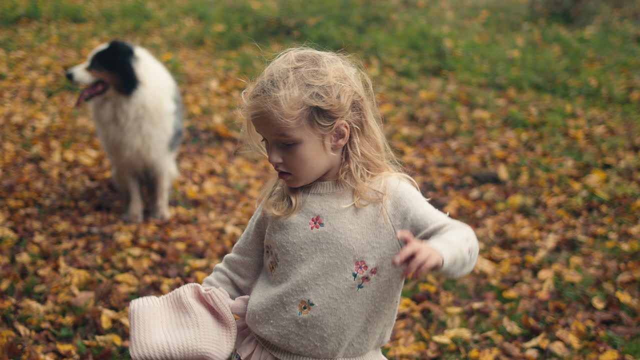 Nuori tyttö ottaa hatun pois ja suoristaa hiuksiaan, koira taustalla.