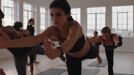 Yoga-Kursgruppe-Gemischtrassiger-Frauen,-Die-Kriegerpose-Praktizieren-Und-Einen-Gesunden-Lebensstil-Genießen,-Indem-Sie-Im-Fitnessstudio-Trainieren-Und-Gruppenmeditation-Bei-Sonnenaufgang-Unterrichten