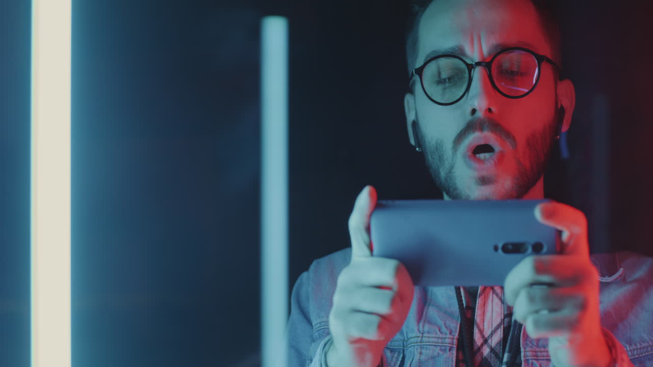 Man Playing Mobile Game Under Neon Lights