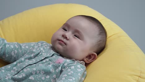 Five-Month-Old-Baby-Girl-In-Flower-Printed-Overall-Lying-On-Her-Back-Cheerfully-Smile