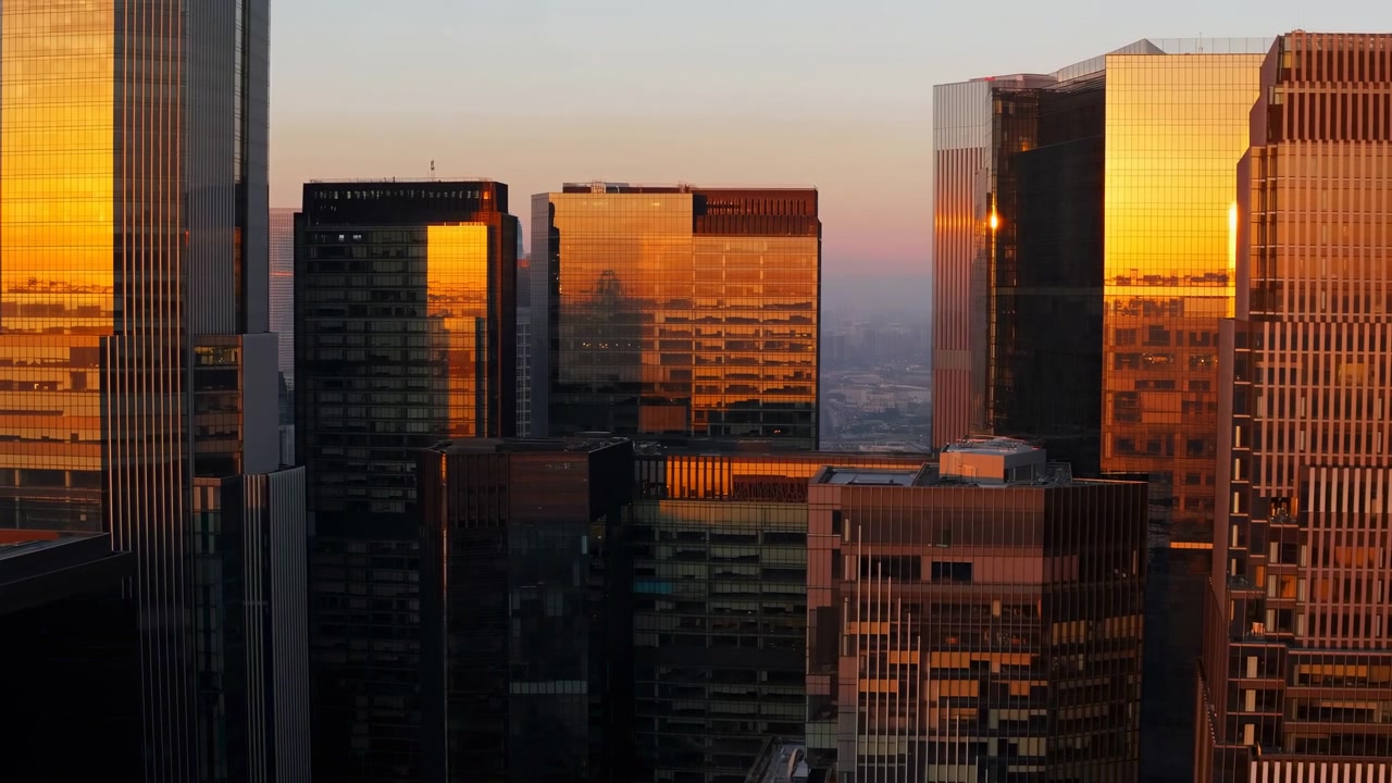 Horizonte al atardecer con reflejos dorados en el cristal, vista aérea de un grupo de rascacielos en el centro, luz naranja cálida
