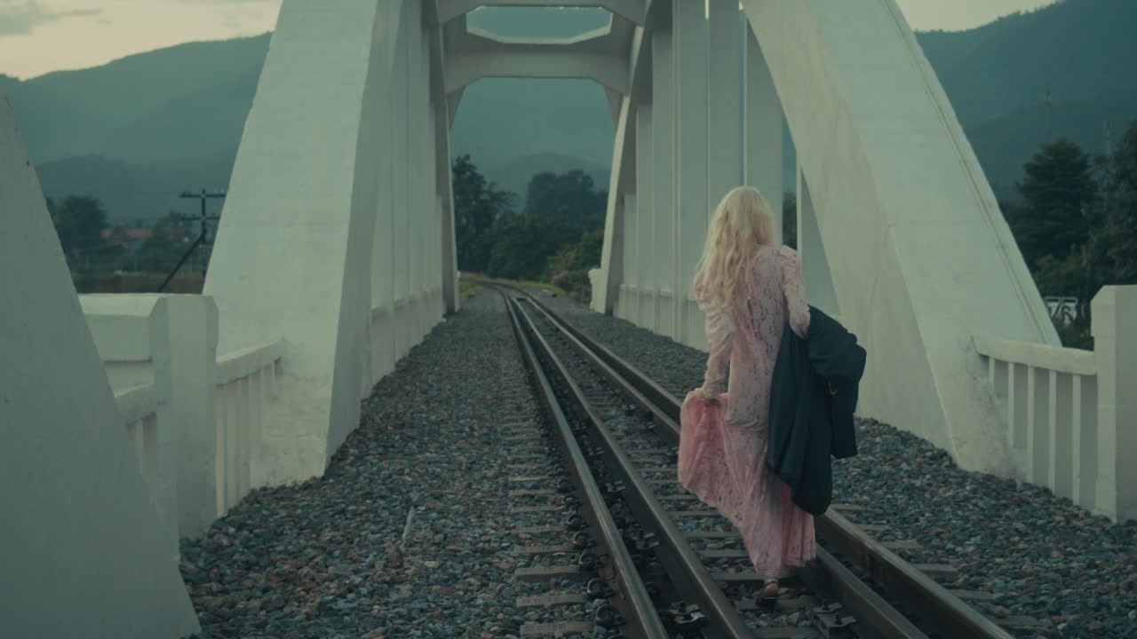 Woman Walking on Train Tracks Over a Bridge